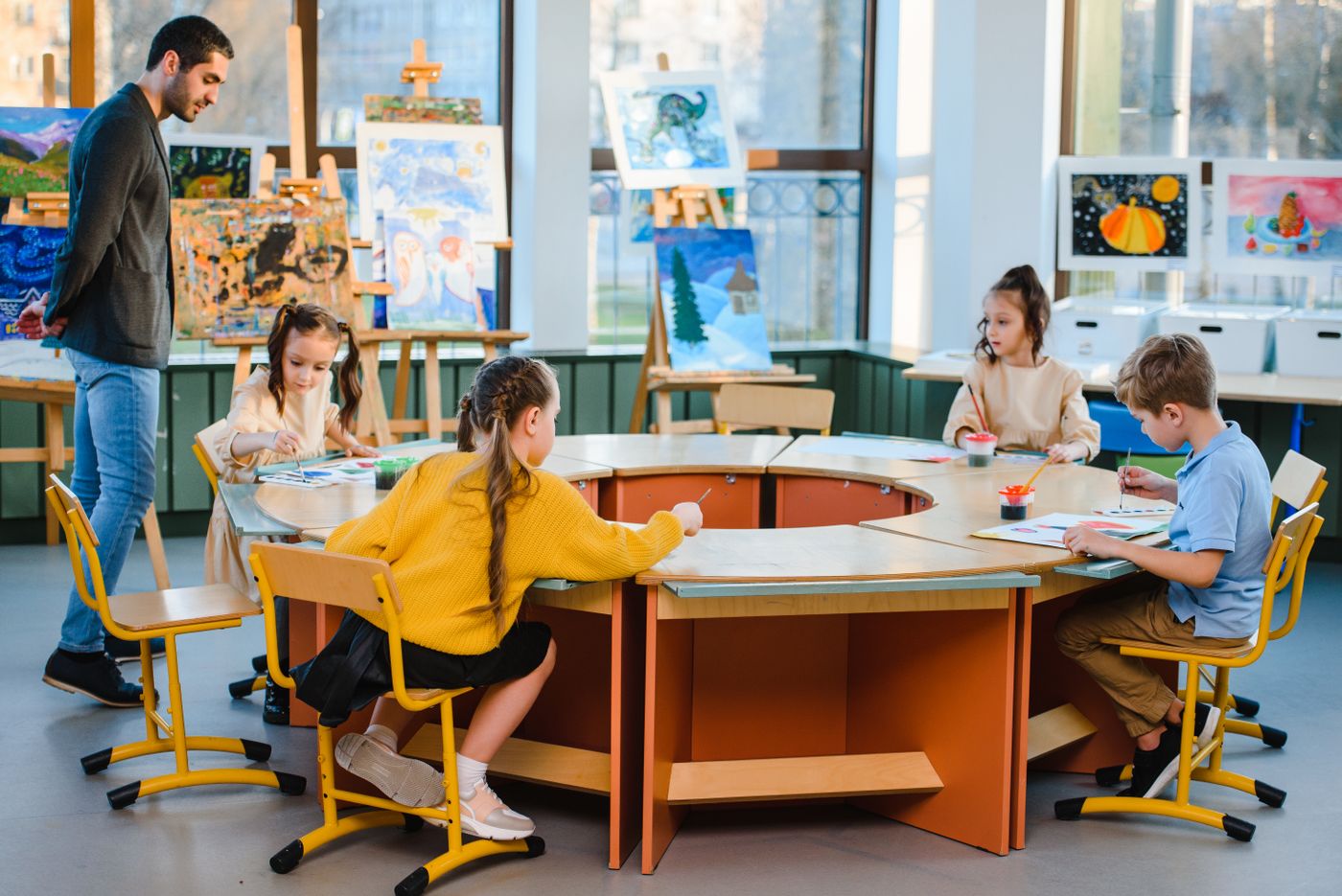 Illustrative pupils in an art class working on paintings with a teacher, not the actual school or pupils